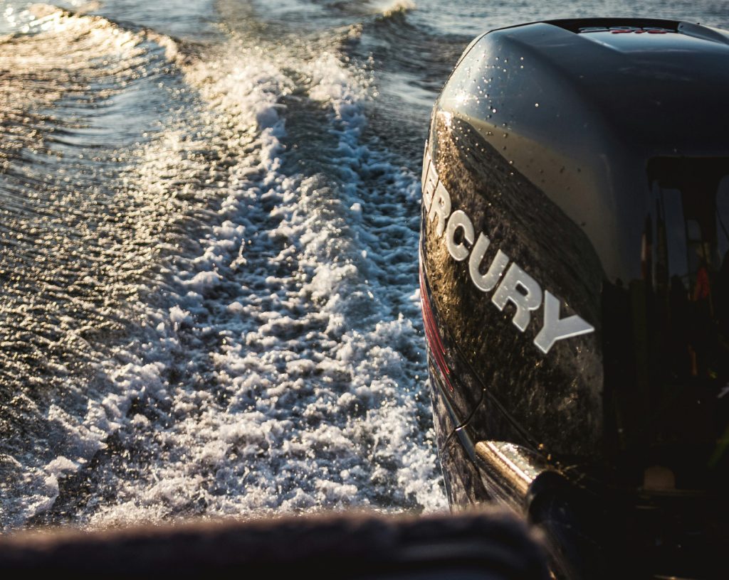 Närbild på en båtmotor utombords av märket Mercury. Varmt solljus lyser på den.